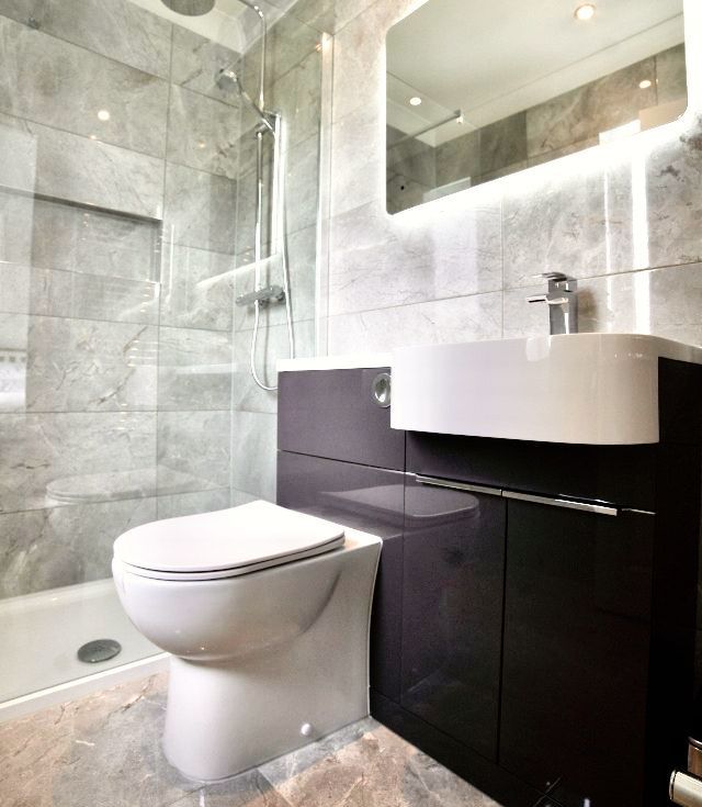 A bathroom with a toilet , sink and shower.