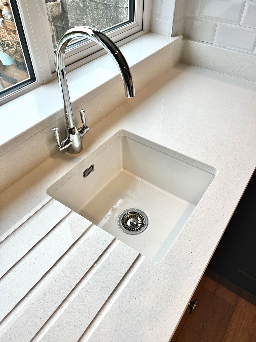 A kitchen sink with a faucet and a window in the background.