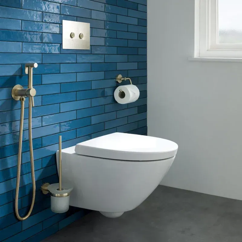 A toilet with a bidet attached to it in a bathroom with blue tiles.