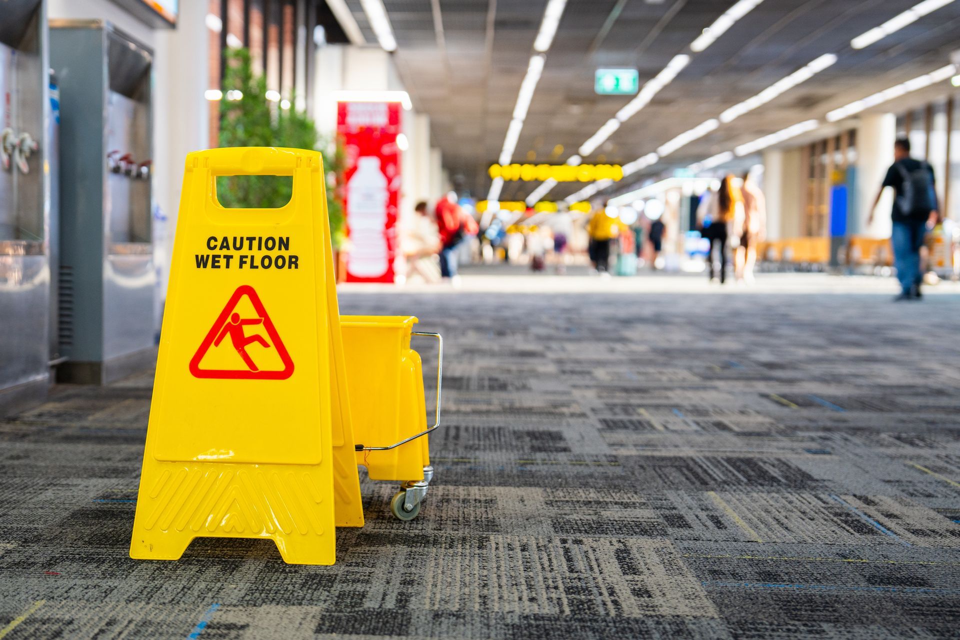 A cleaning cart with mop and buckets in a hallway.
