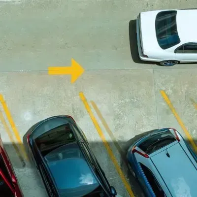 A car driving past parked vehicles on the newly constructed parking facility foundation in Dunedin.
