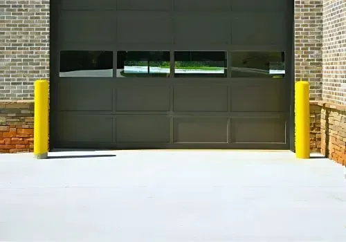 A freshly poured white concrete driveway leads to a garage for business vehicles in Kaikorai Valley.