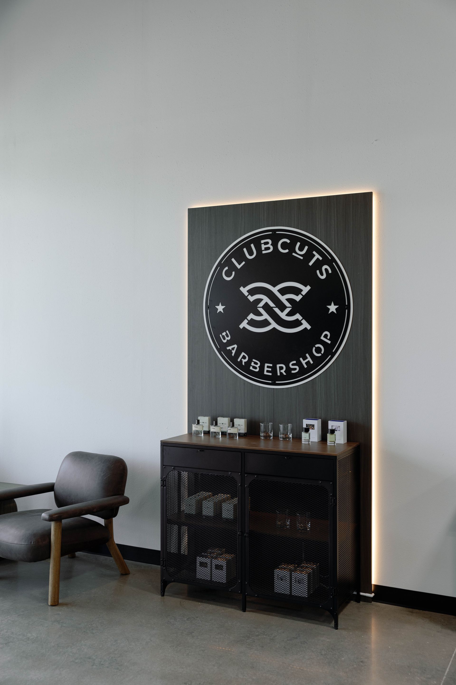 Clubcuts barbershop interior with logo, product display, and waiting chair.