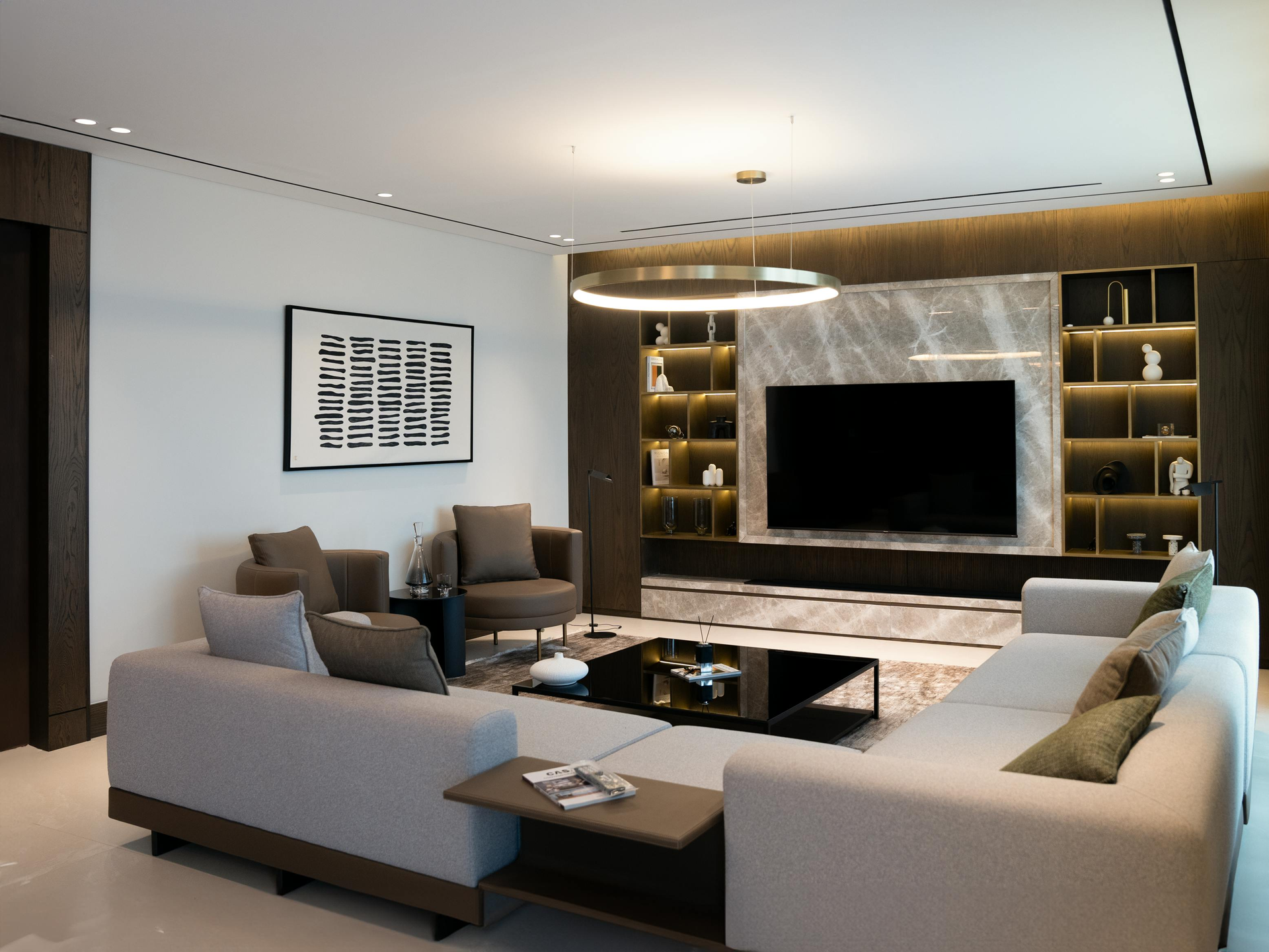Modern living room with gray couches, a large TV, and built-in shelving.
