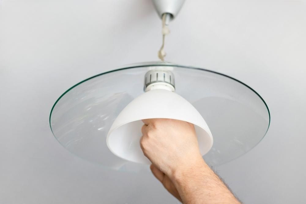 A person is changing a light bulb in a ceiling light.