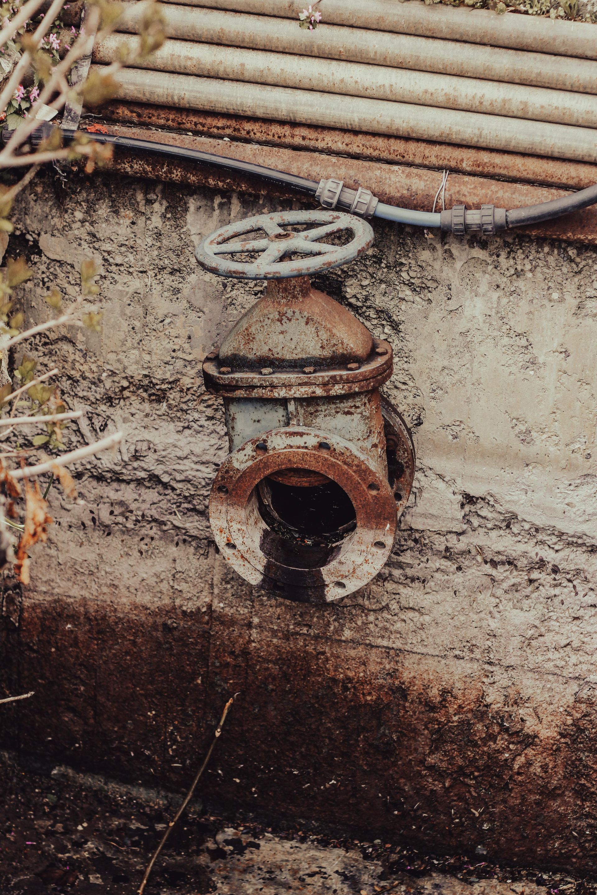 A close up of a rusty valve on a wall