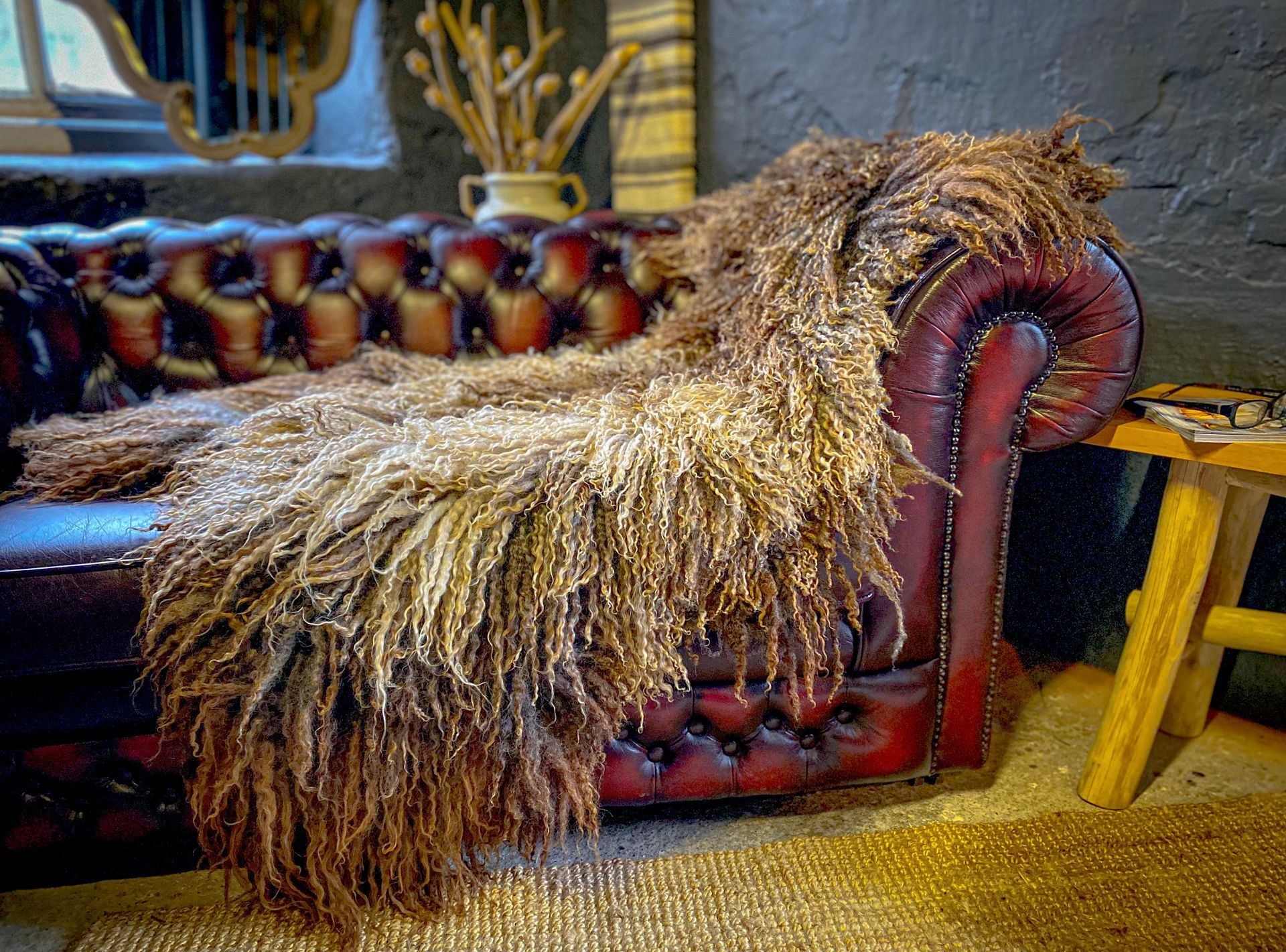 Large long wool felted fleece rug by Karolina Begier draped over a sofa, showcasing its scale, texture and natural movement.