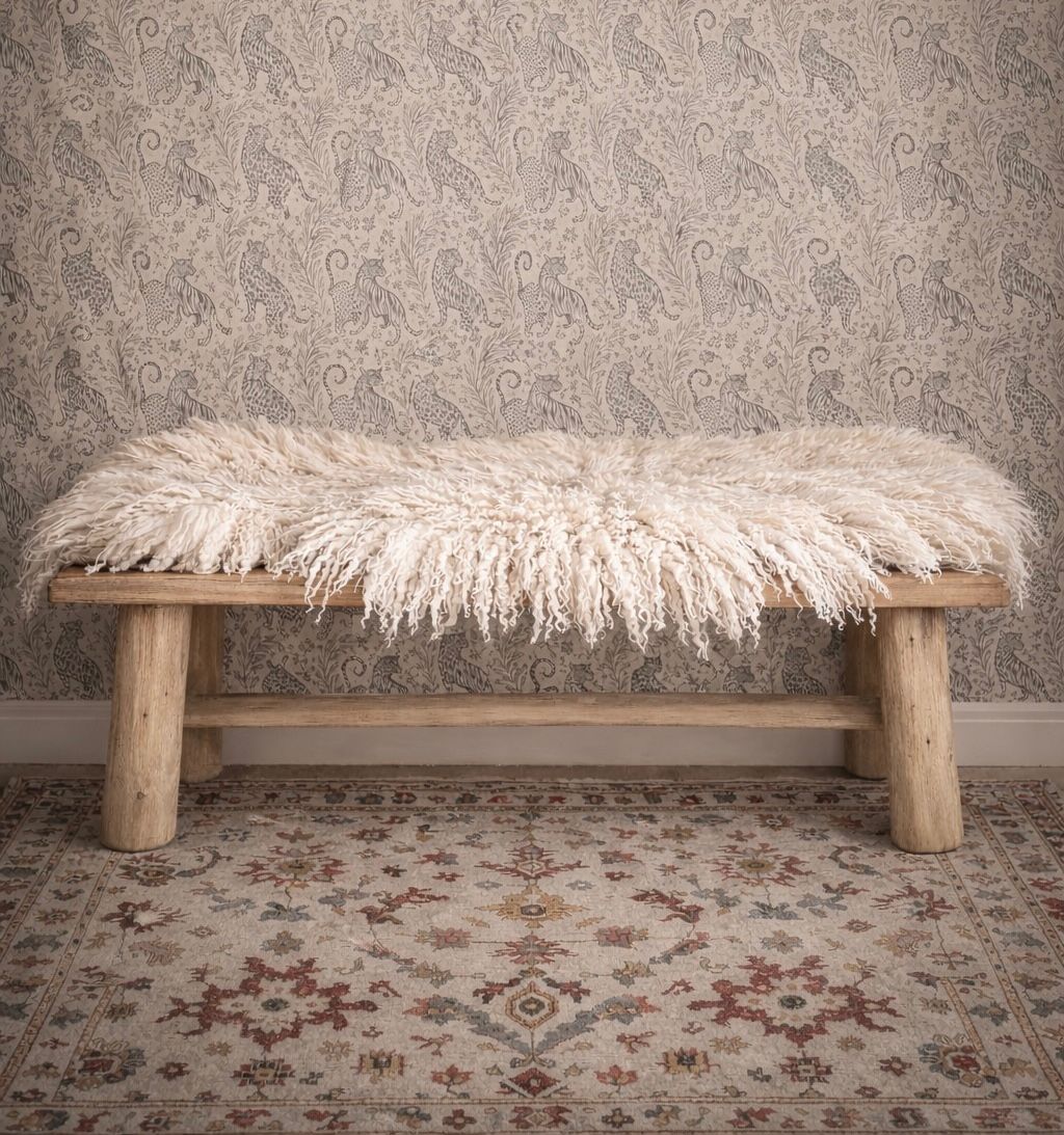 Rustic wooden bench with cream felted fleece rug against tiger print wallpaper and vintage rug.