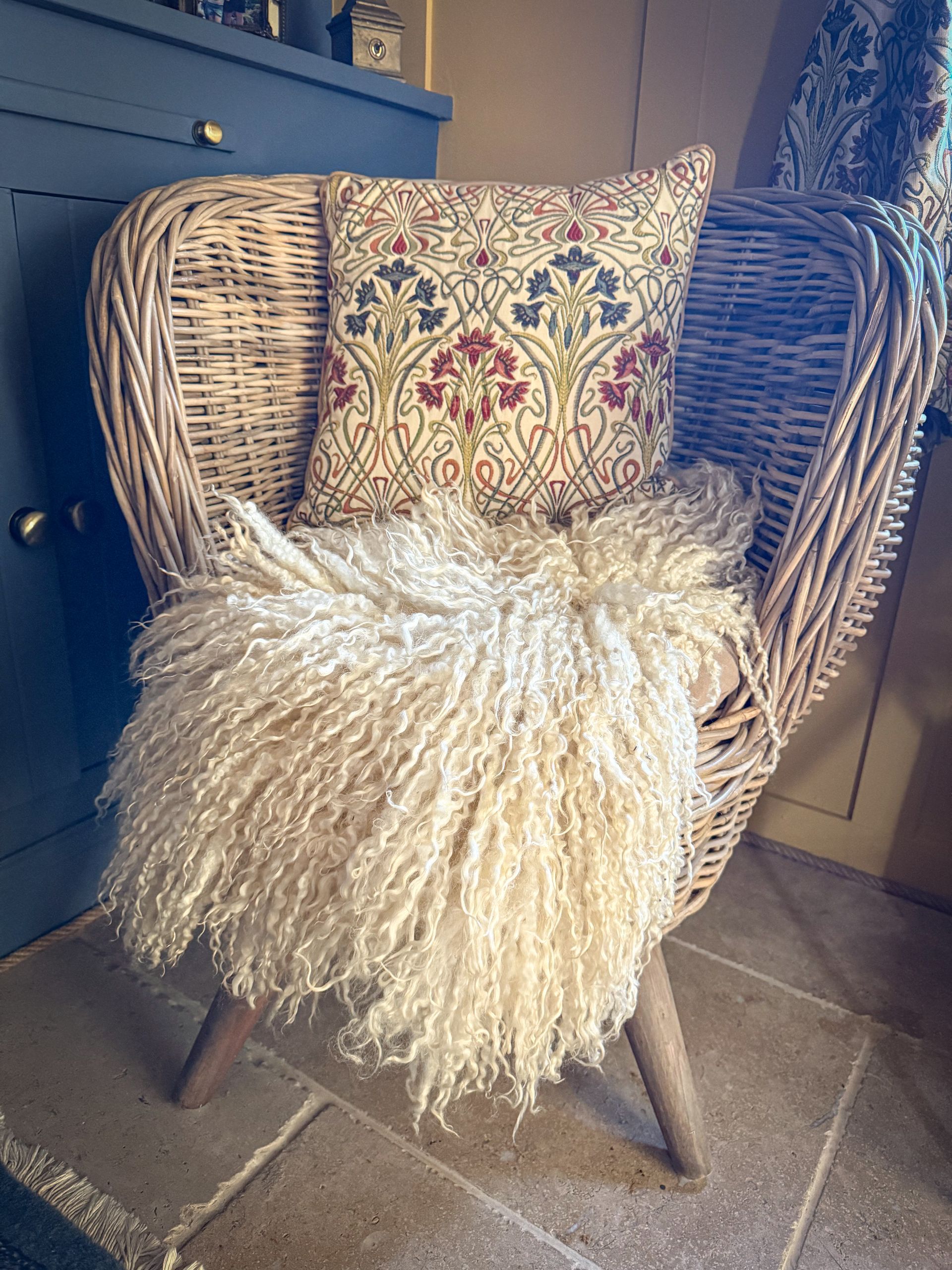 Small felted fleece rug by Deborah Griffin styled on a chair as a natural wool seat pad, showcasing its versatility and rustic texture.