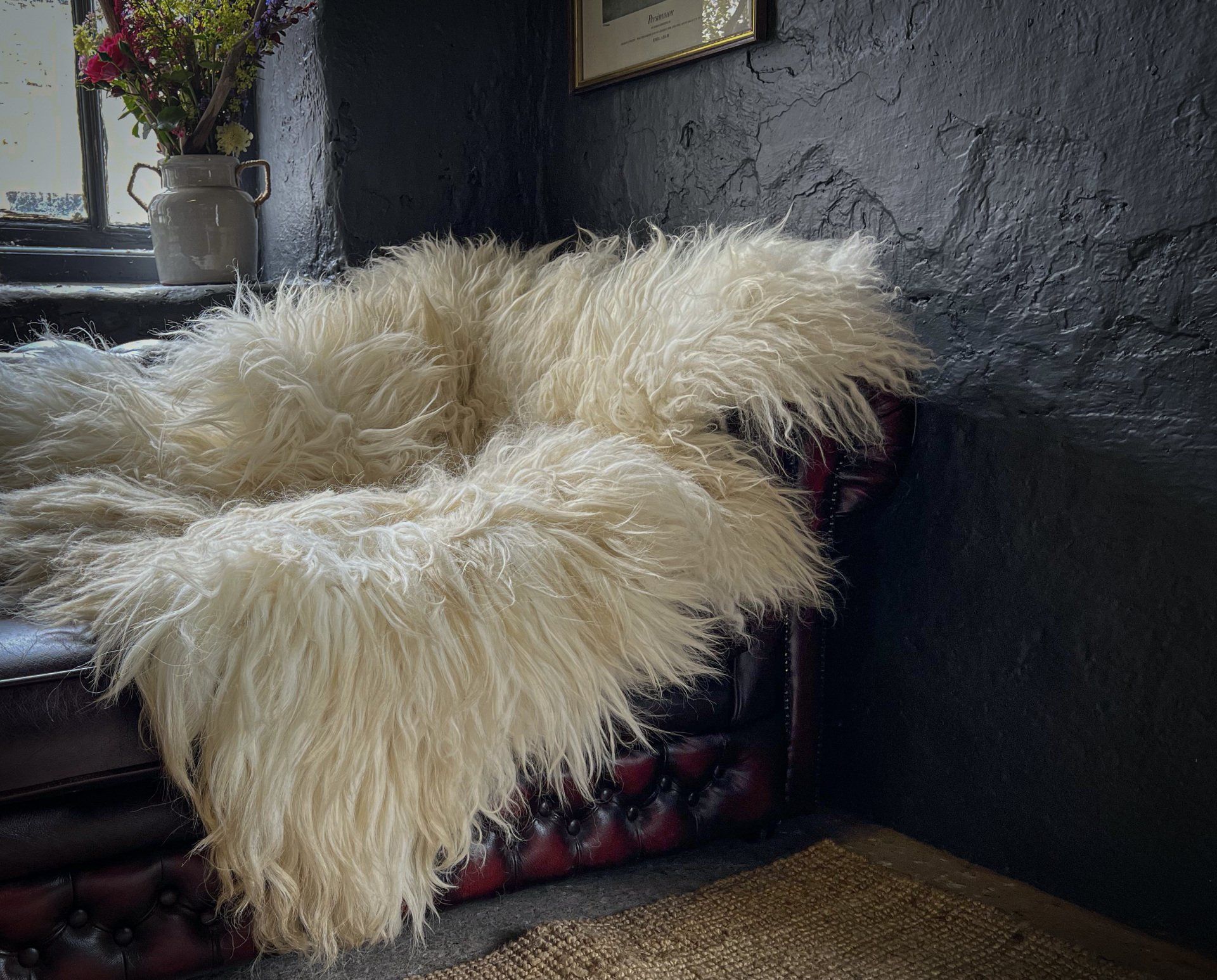 White felted fleece rug by Deborah Griffin draped over a sofa, featured on the back of a magazine and used as the opening image of the website.