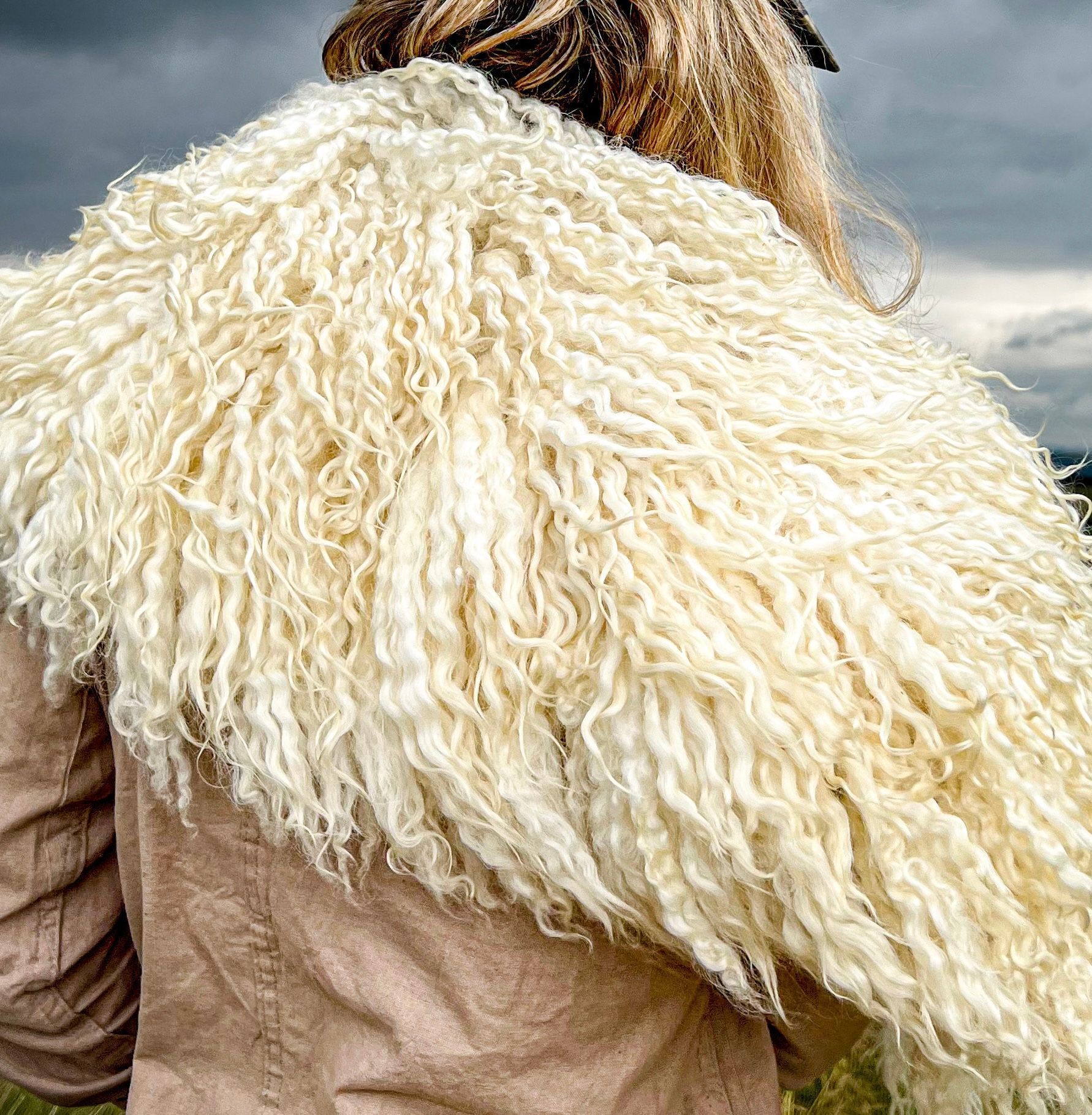 Visitor wearing a small wild wool collar felted fleece piece by Deborah Griffin as a collar, photographed during a Piglet in Bed feature on the Felted Fleece Collective, overlooking the landscape.