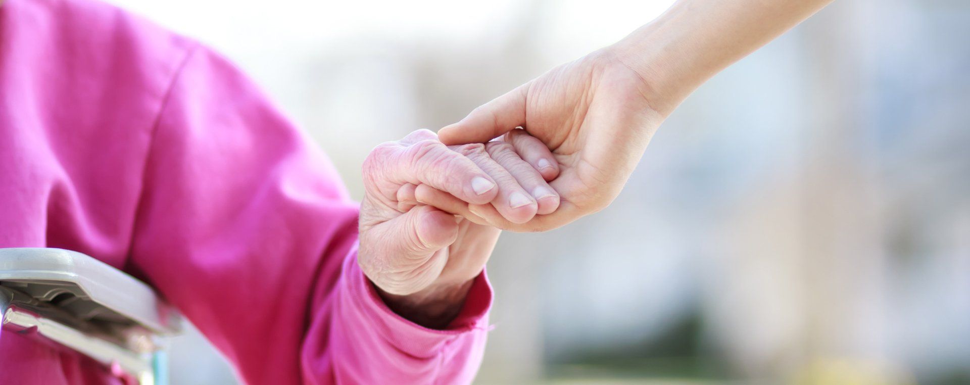 Image of the hand of a caregiver gently grasping the hand of a resident