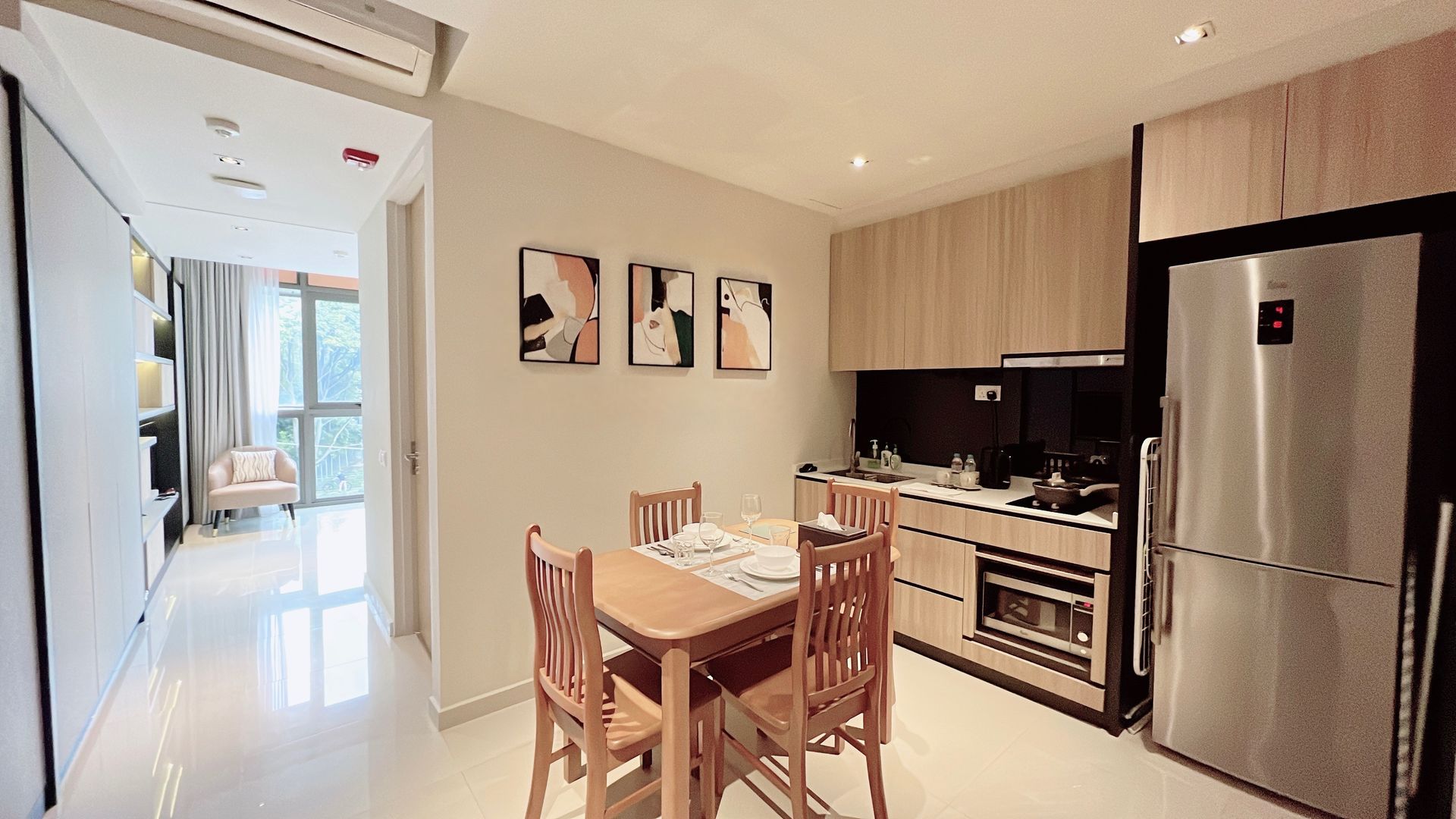 Modern kitchen and dining area with wooden table, stainless fridge, and bright hallway beyond
