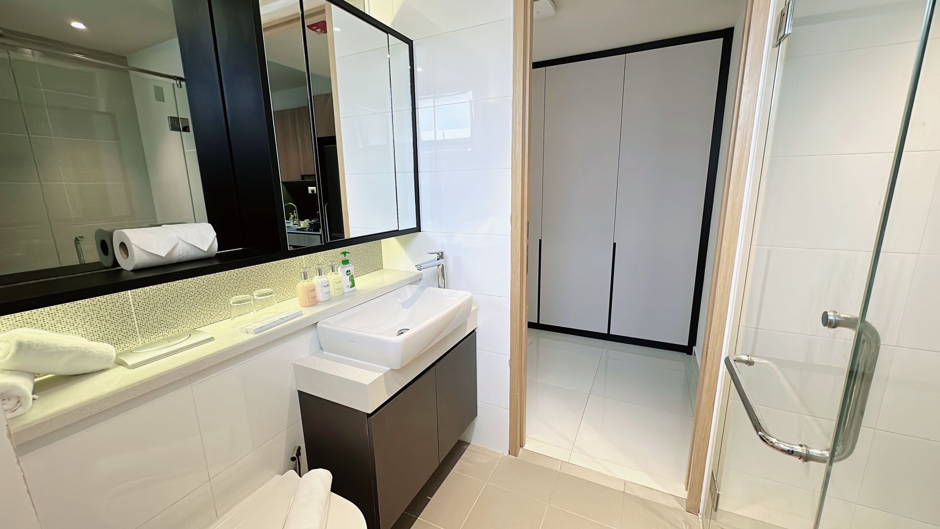 Bright modern bathroom with vanity, sink, mirror cabinet, and glass shower door