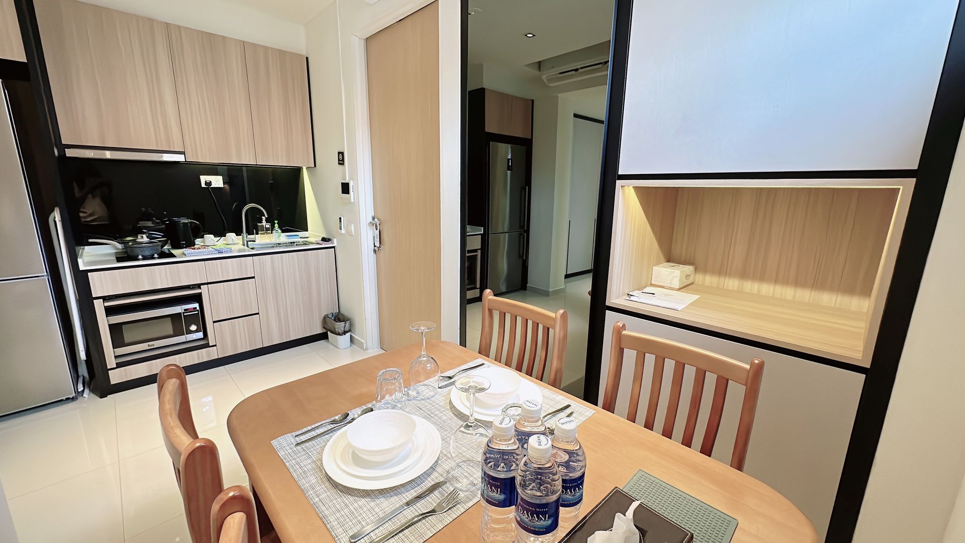 Dining table in a small apartment kitchen with plates set and a compact kitchenette in the background