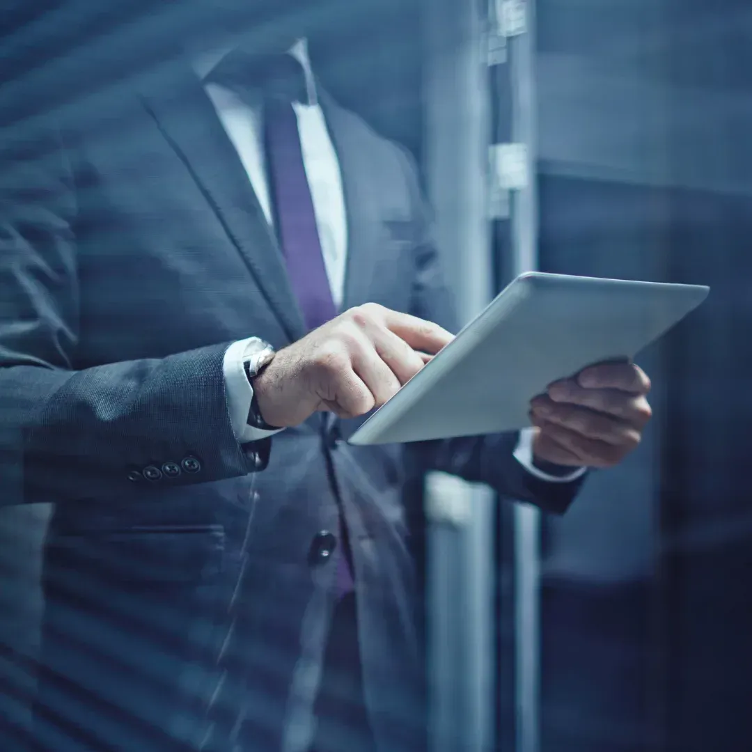 Un homme en costume et cravate utilise une tablette.