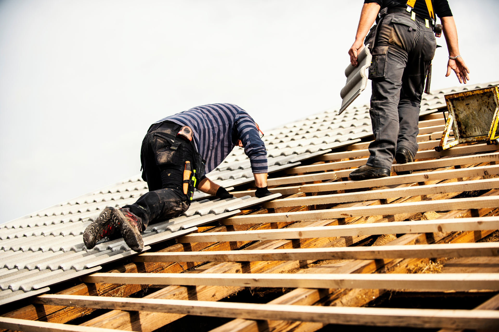 Deux hommes travaillent sur le toit d'un immeuble.