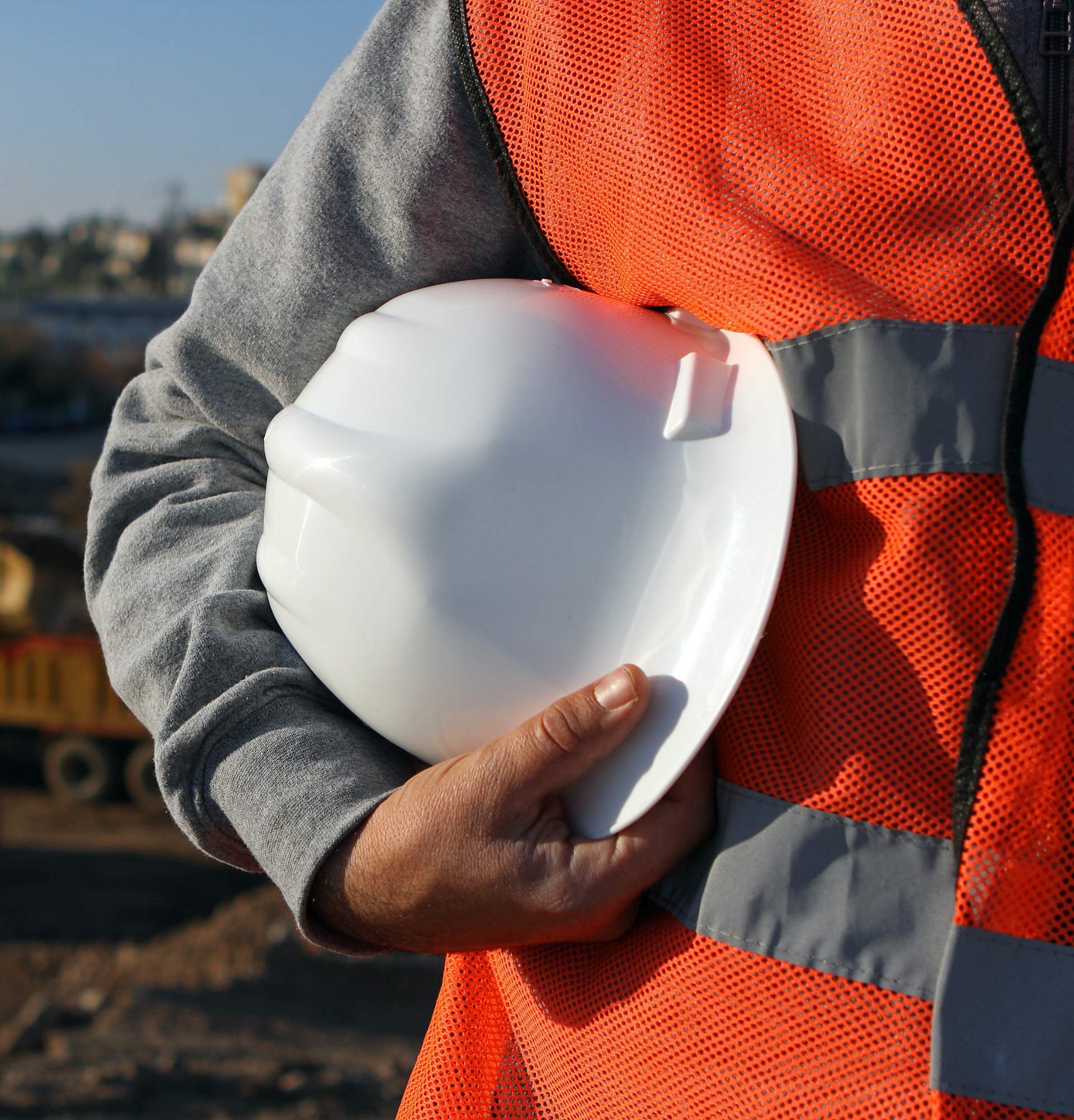 Un homme portant un gilet orange tient un casque blanc