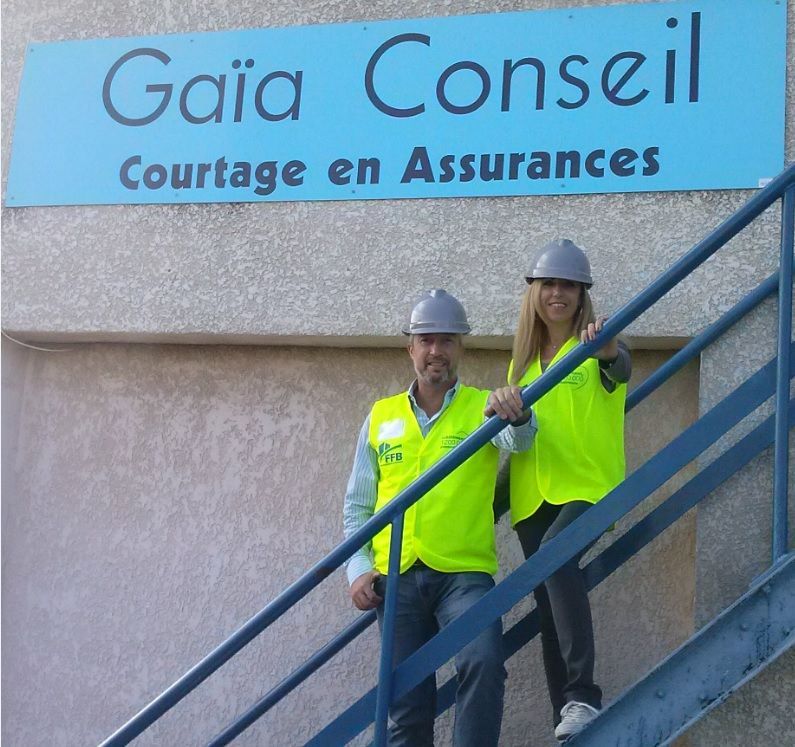 Un homme et une femme debout sur un escalier sous un panneau indiquant gaia conseil