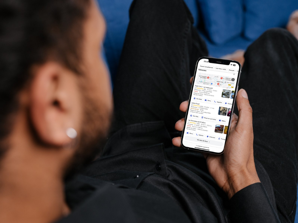 Un homme est allongé sur un canapé et tient un téléphone portable.
