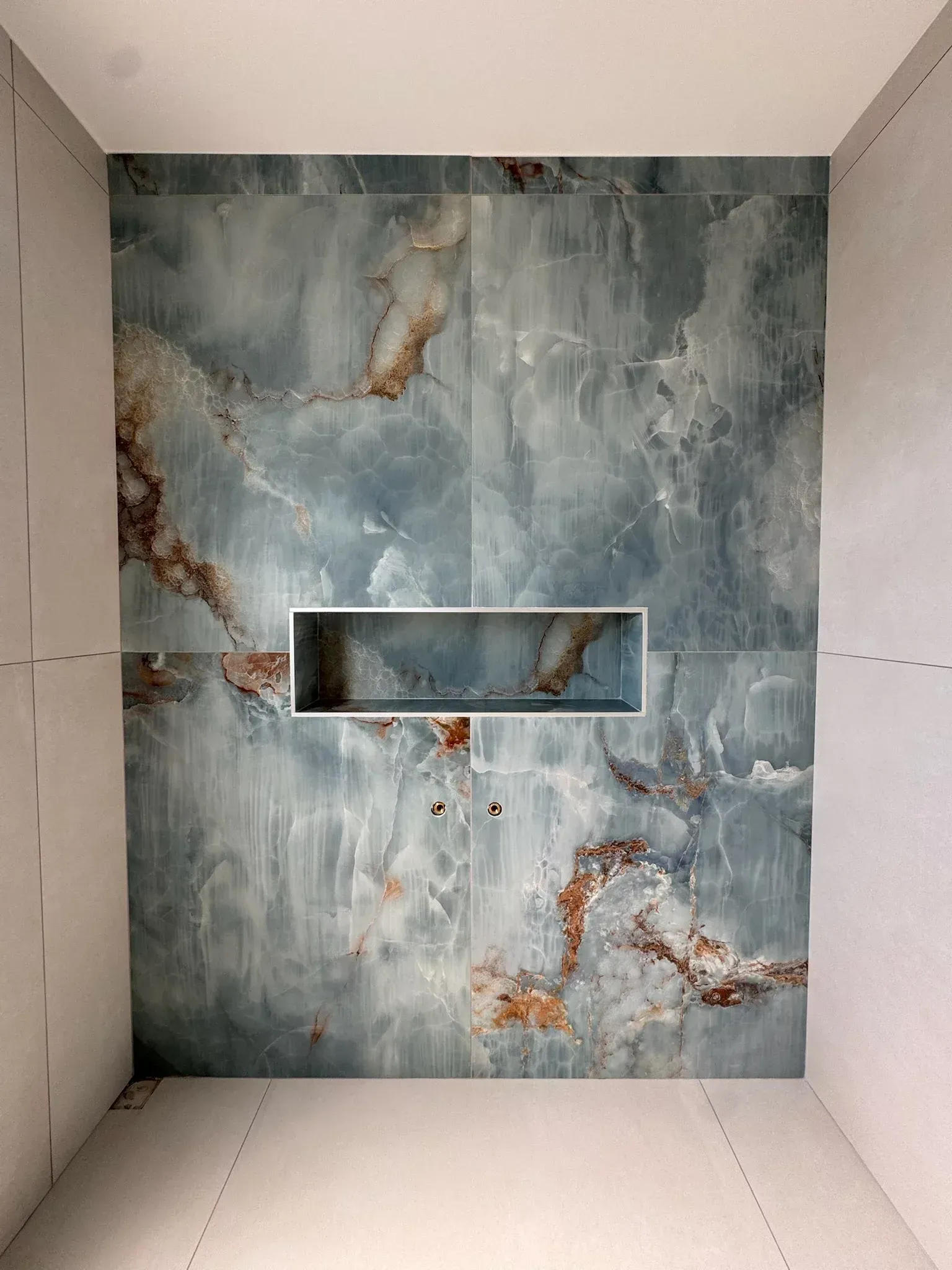 Une salle de bain avec un mur en marbre et une niche dans le mur.