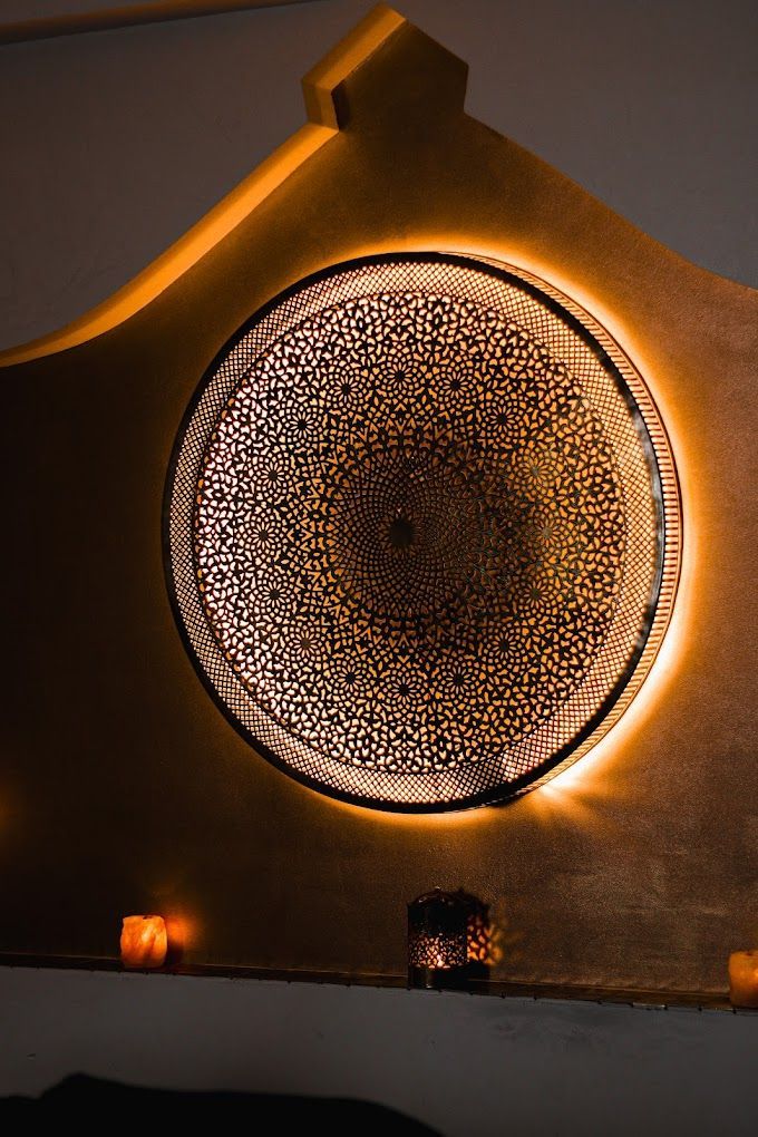 Un mur avec un motif circulaire dessus est éclairé la nuit.