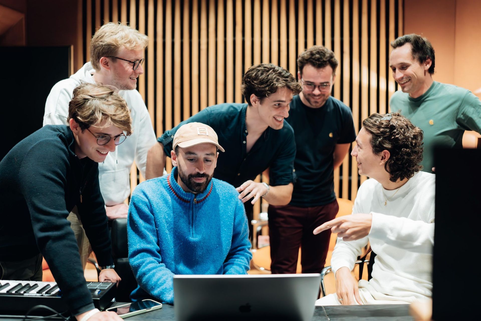 Un groupe de jeunes hommes regardent un ordinateur portable.