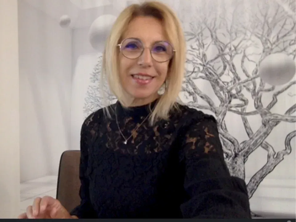 Une femme portant des lunettes et un haut noir sourit