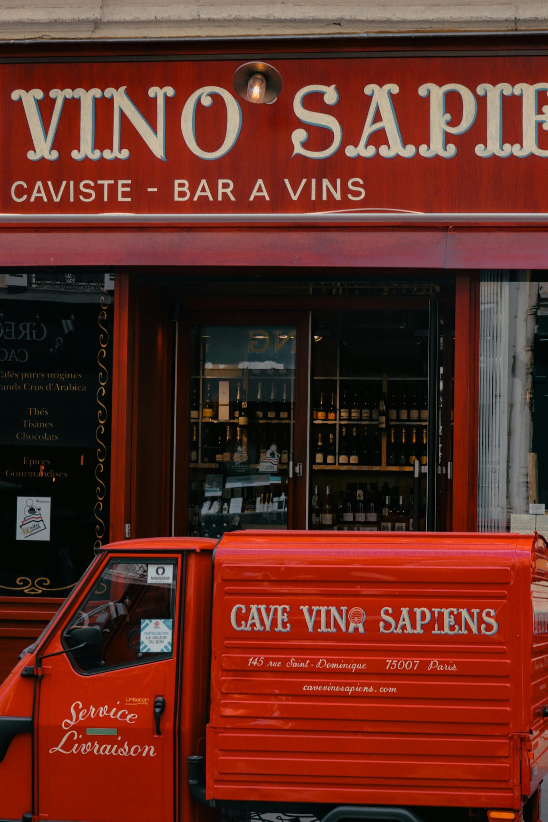 Un camion rouge est garé devant un magasin appelé vino sapin