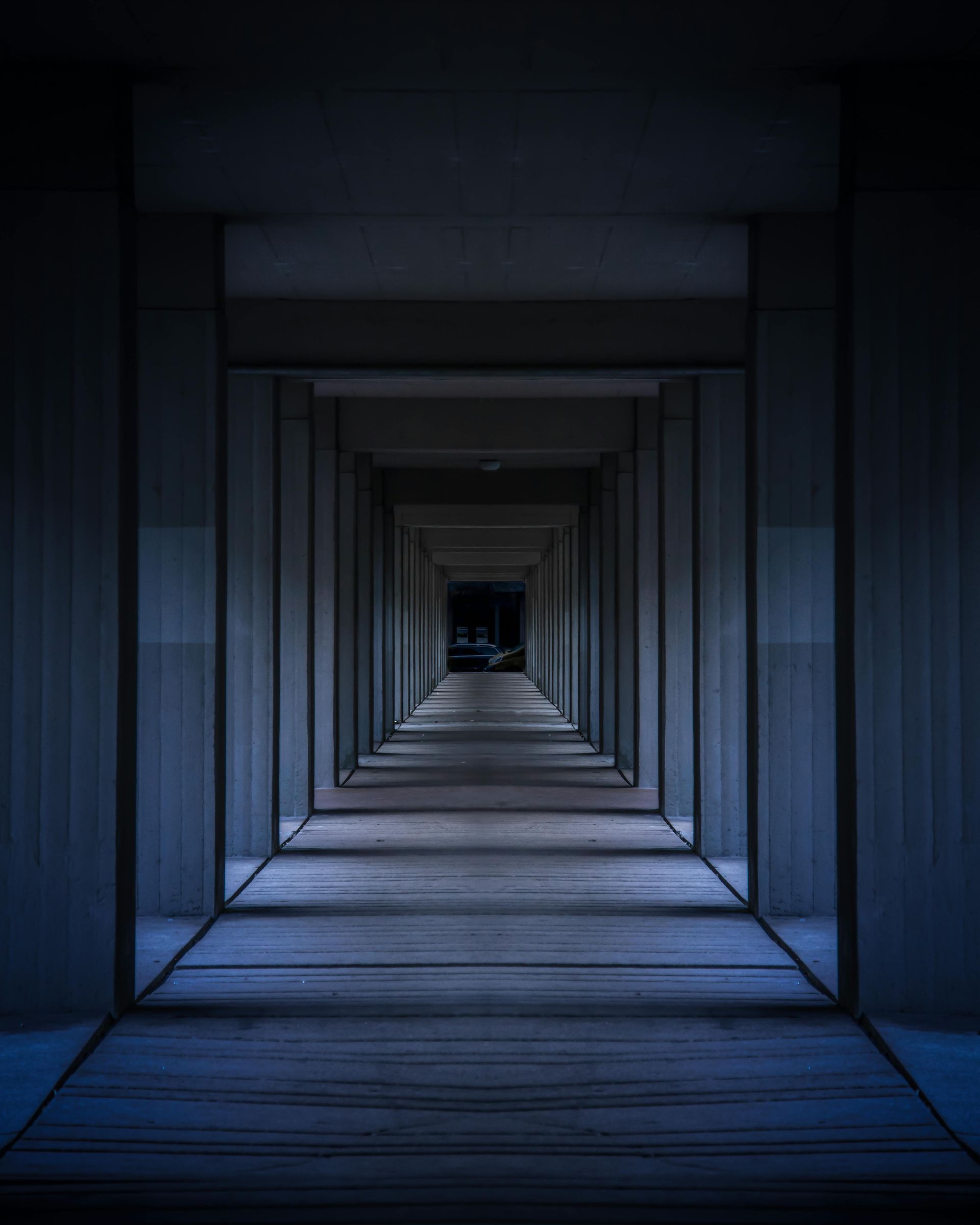 Un long couloir étroit avec des colonnes et un fond sombre.