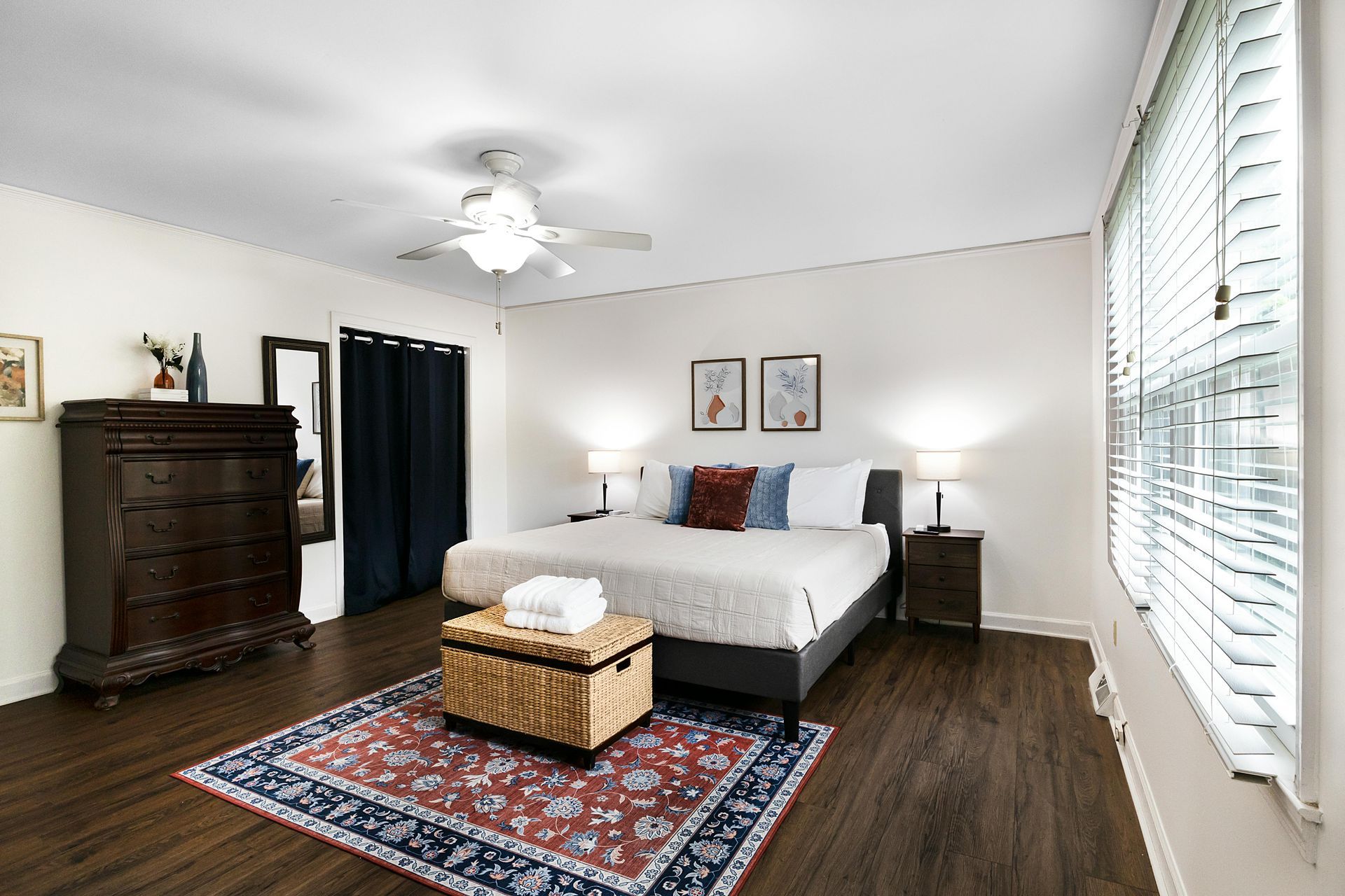 Une chambre avec un lit king size, une commode, un tapis et un ventilateur de plafond.