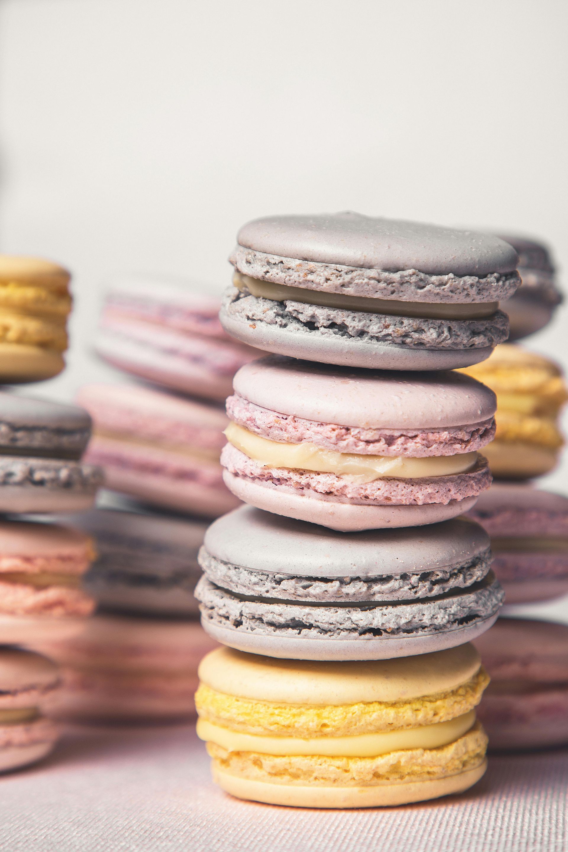 Pile de macarons colorés fourrés à la crème sur une surface blanche.