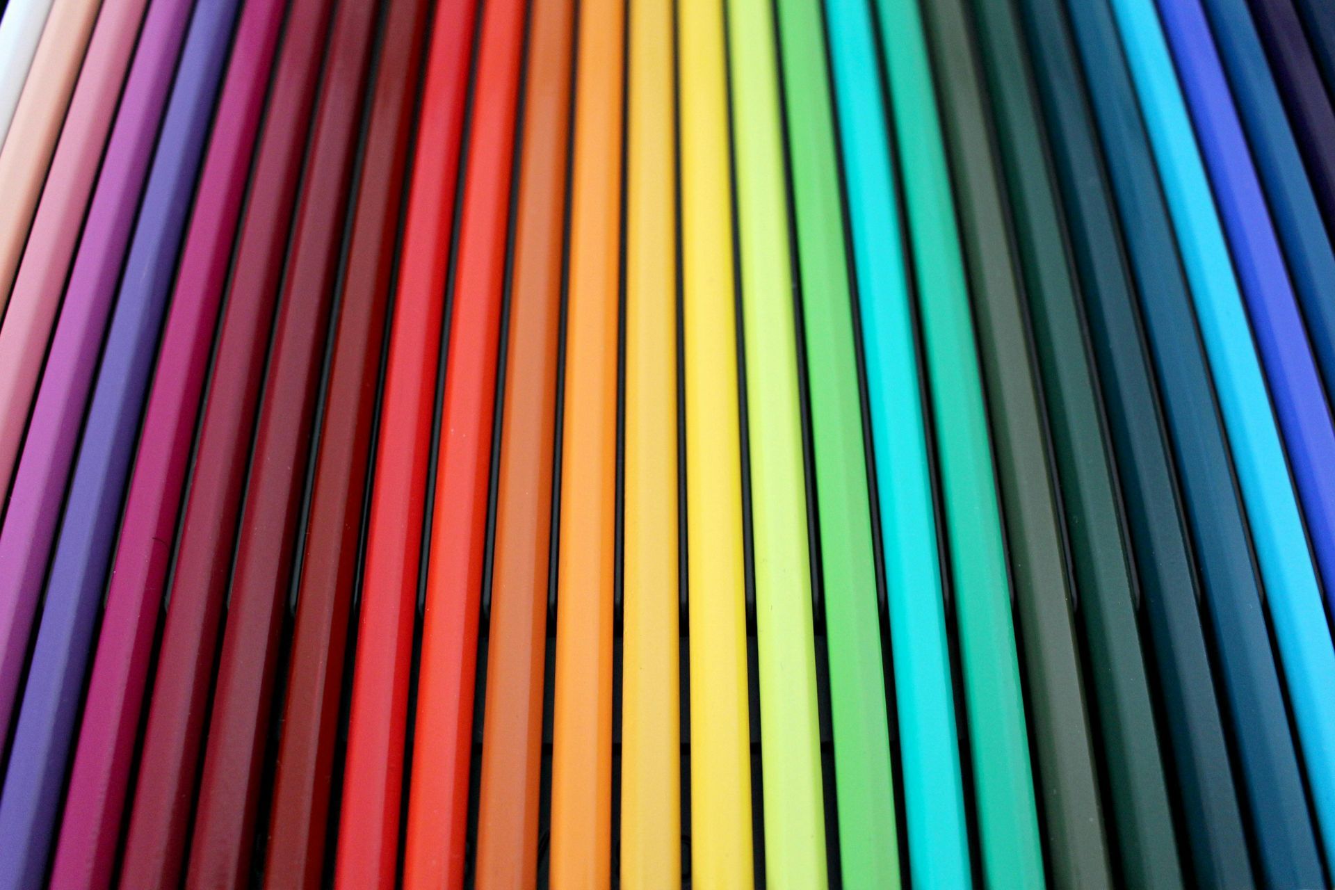 Rows of colored pencils arranged in a rainbow gradient, showing a spectrum of hues.
