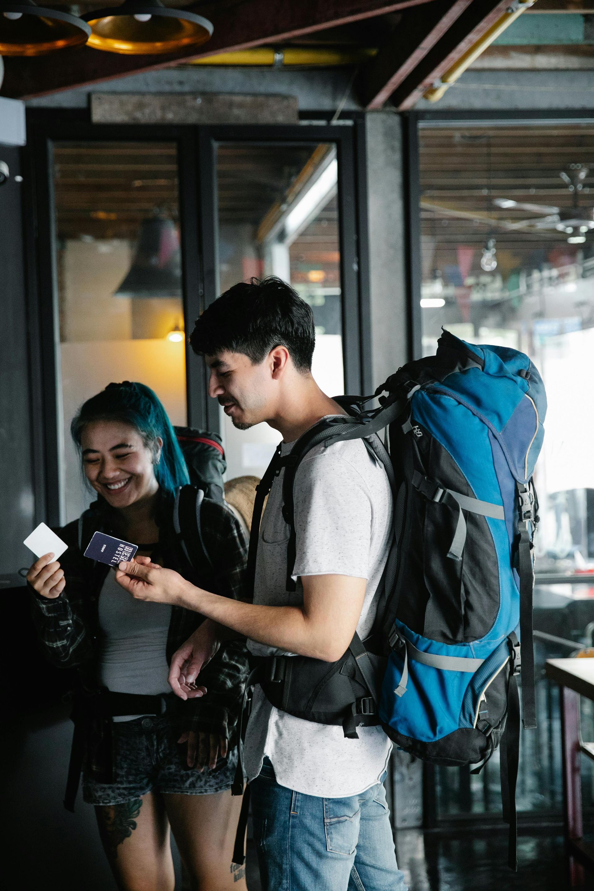 Un homme avec un sac à dos se tient à côté d'une femme aux cheveux bleus.
