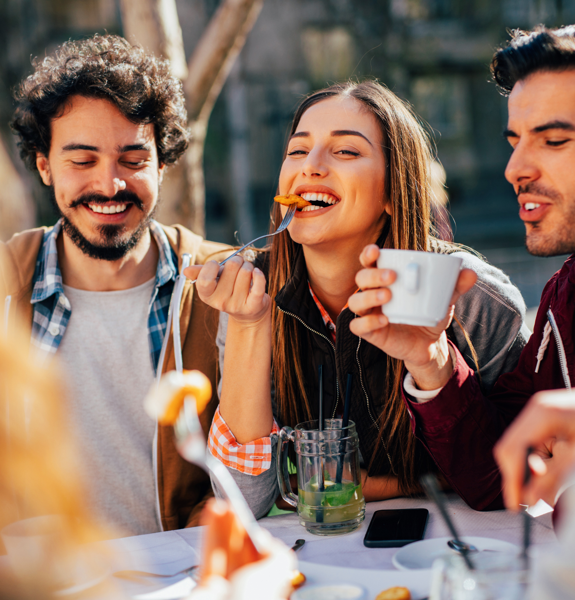 Un groupe de personnes sont assises à une table en train de manger de la nourriture et de boire du café.