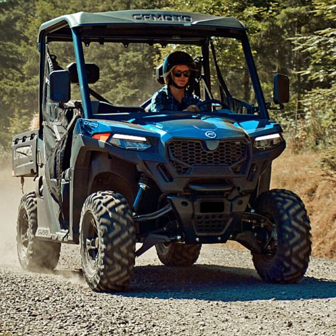 A Man Is Driving A Blue Atv On A Dirt Road — Coastal Farm & Motorcycles In Innisfail, QLD