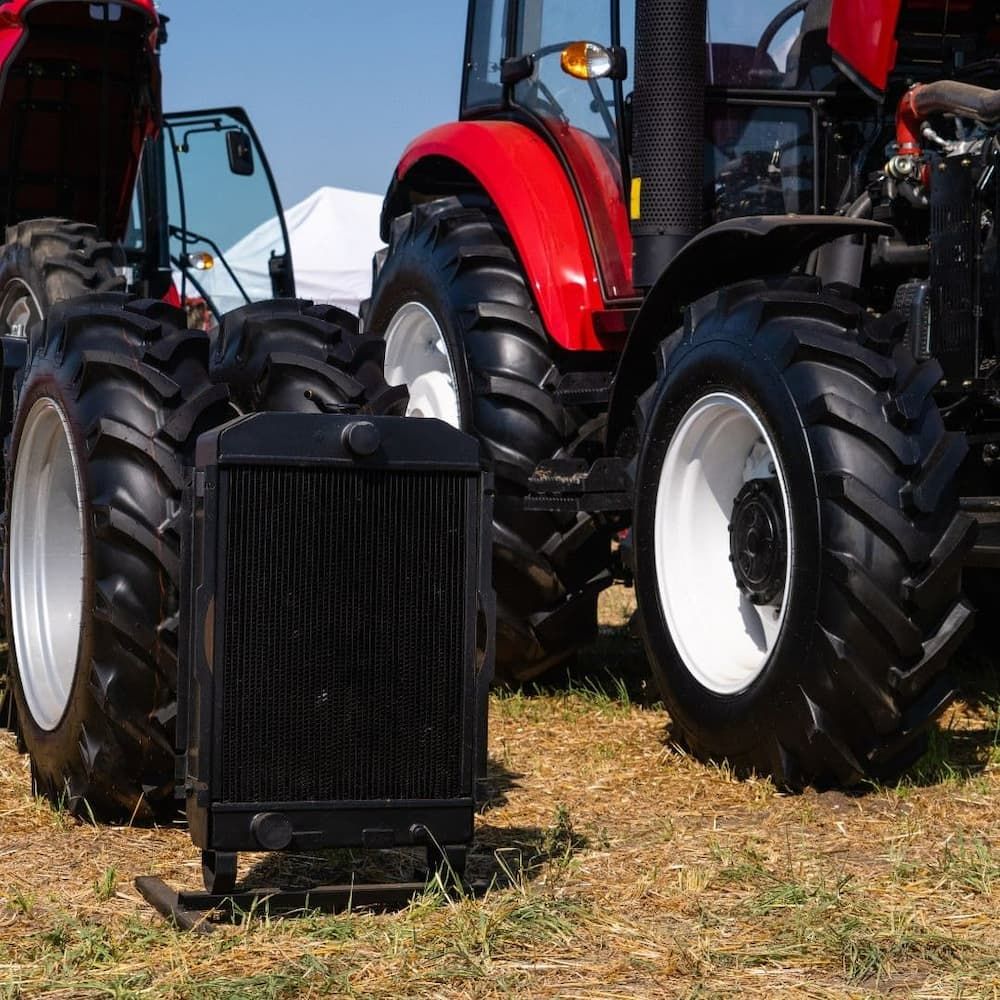 A Red Tractor Is Parked Next To A Black Radiator — Coastal Farm & Motorcycles In Tully, QLD