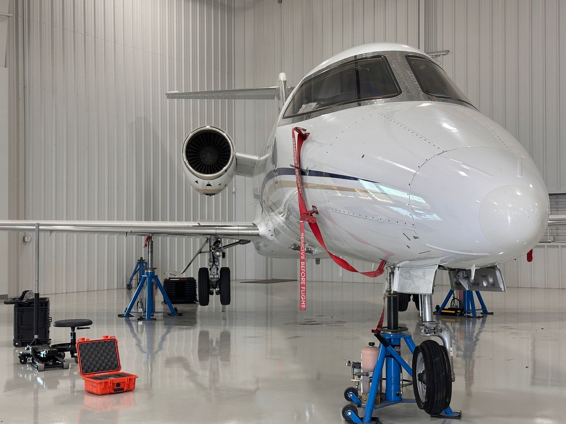 Two men are working on an airplane engine in a hangar.