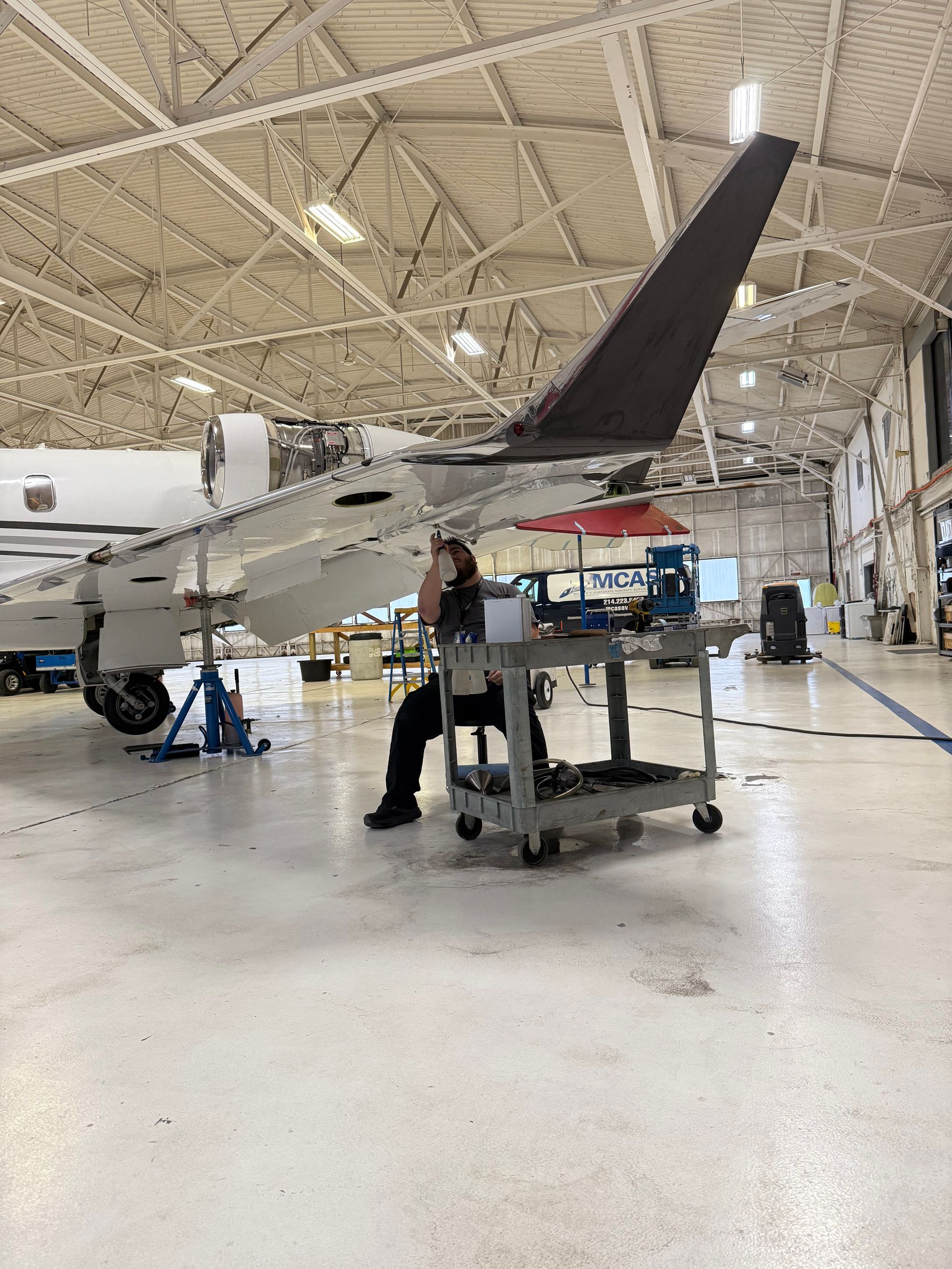 A man is working on an airplane engine in a factory.