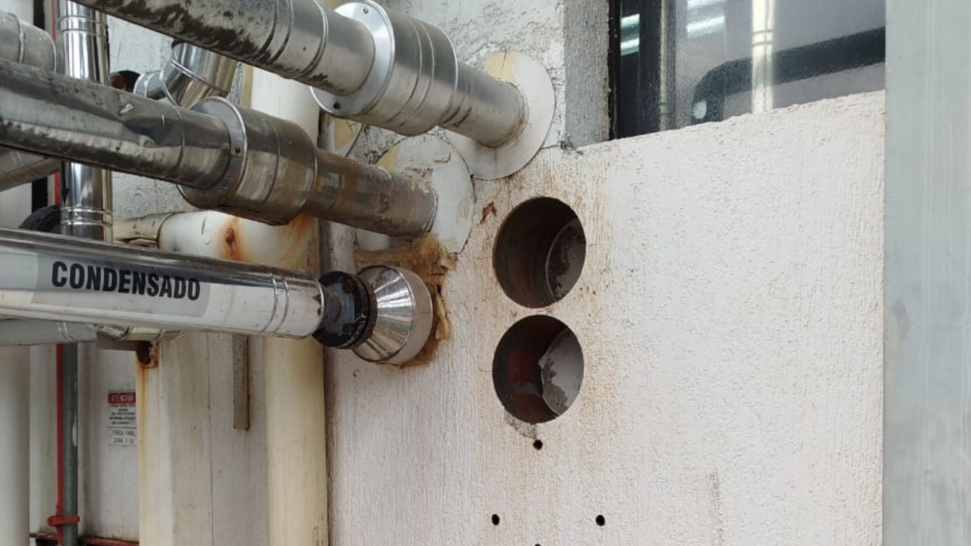 Una pared con tuberías que salen de ella y dos agujeros en ella.