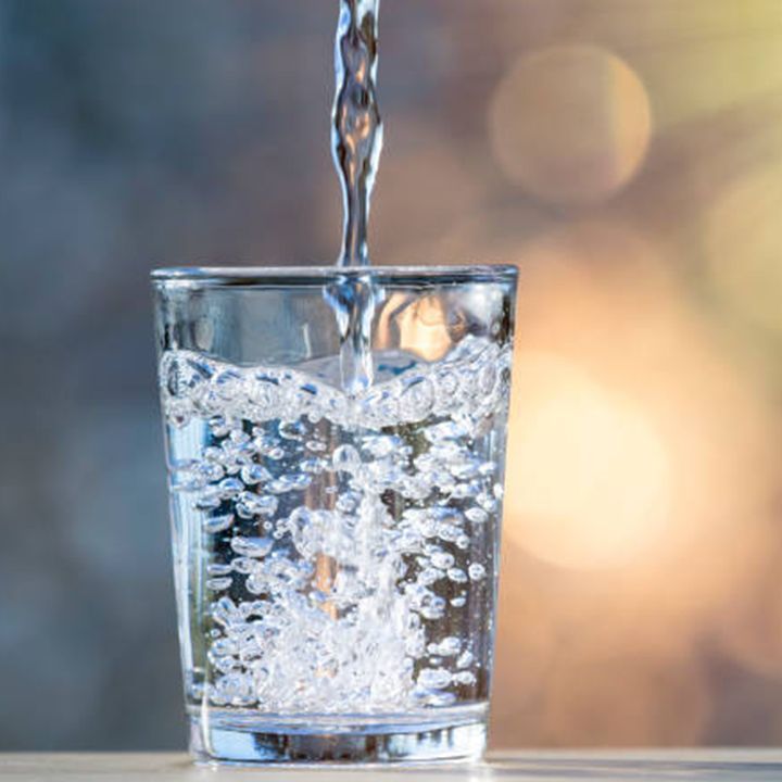 Water is being poured into a glass on a table.