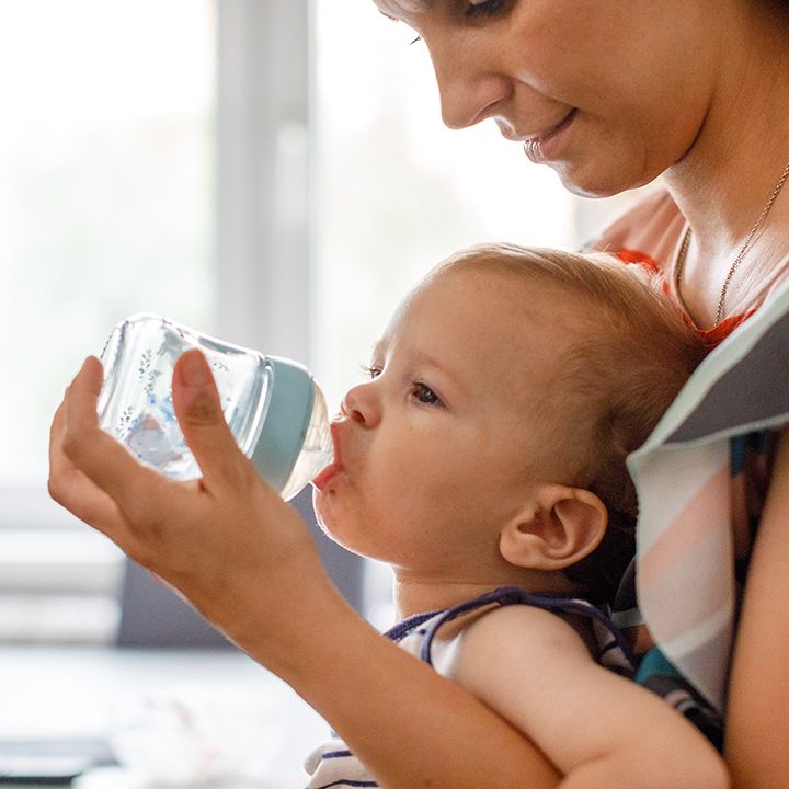 A woman is holding a baby who is drinking from a bottle.