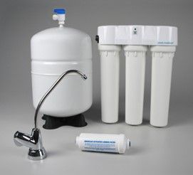 A water filter is sitting on a table next to a faucet.