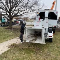 A man is standing next to a tree chipper in a yard.