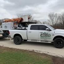 A white truck with a crane on the back is parked on the side of the road.