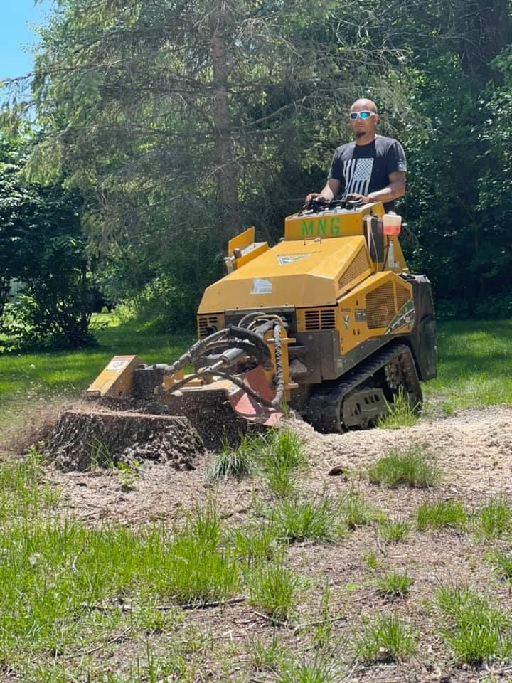 A man is driving a stump grinder in a field.