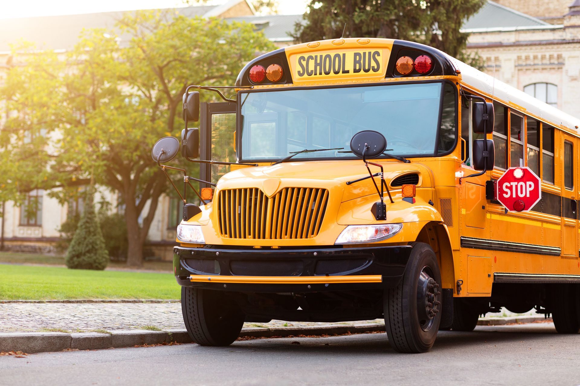Yellow school bus parked curbside near building; stop sign visible.