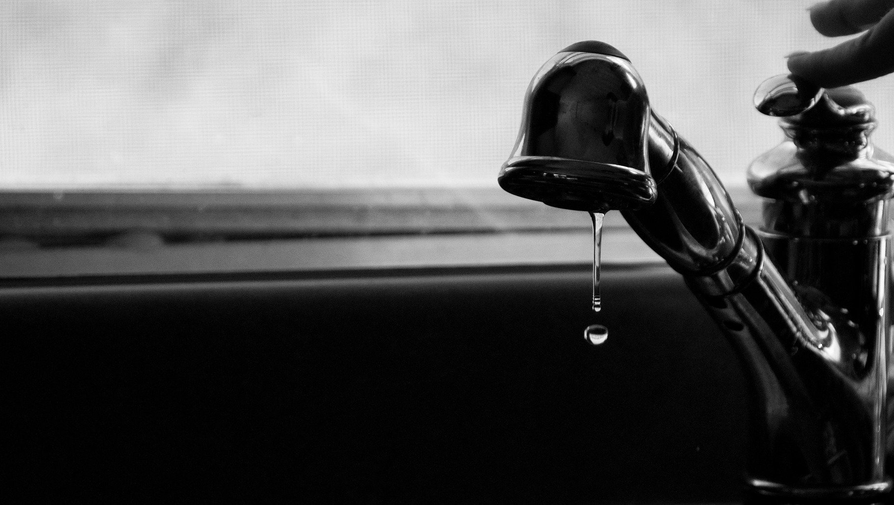 A black and white photo of a faucet with water dripping from it