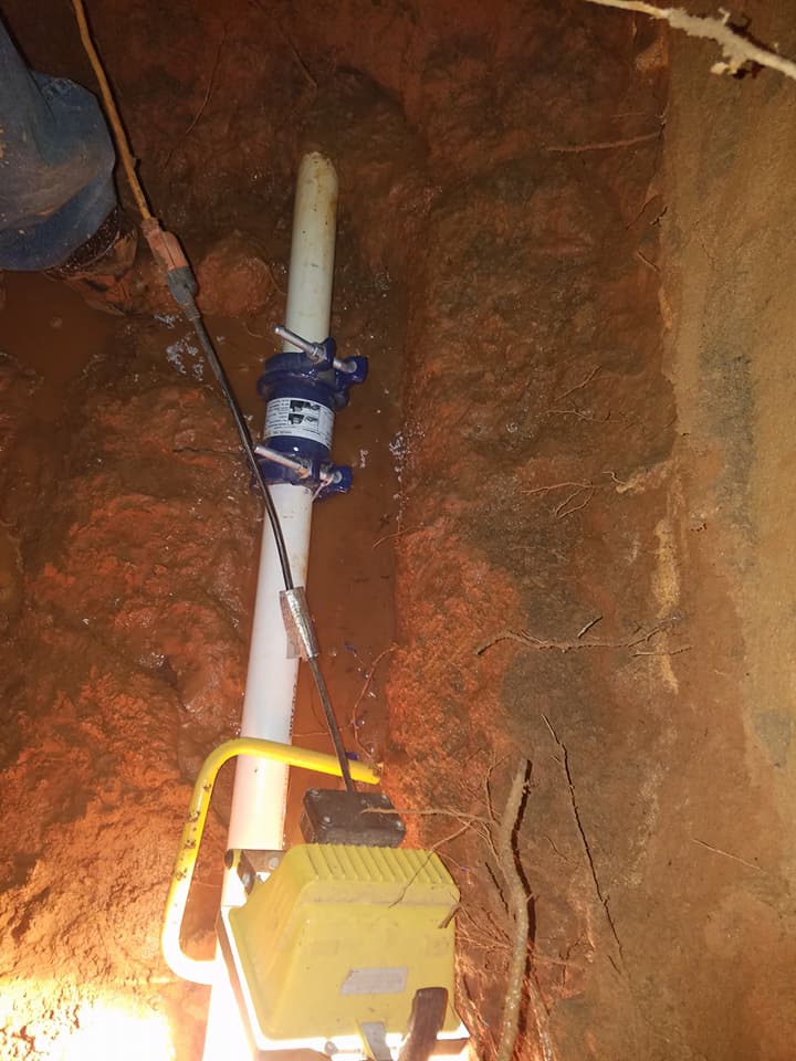 A white pipe is sitting in the dirt next to a yellow box.