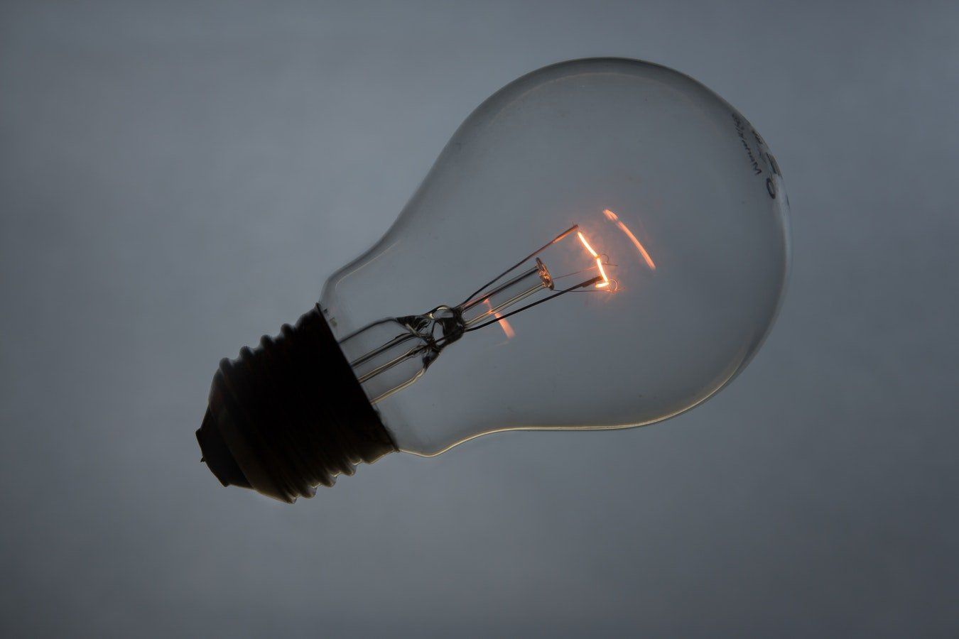 A light bulb is glowing in the dark against a cloudy sky.